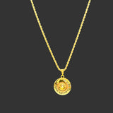 Gold necklace with a round pendant on a black velvet stand.