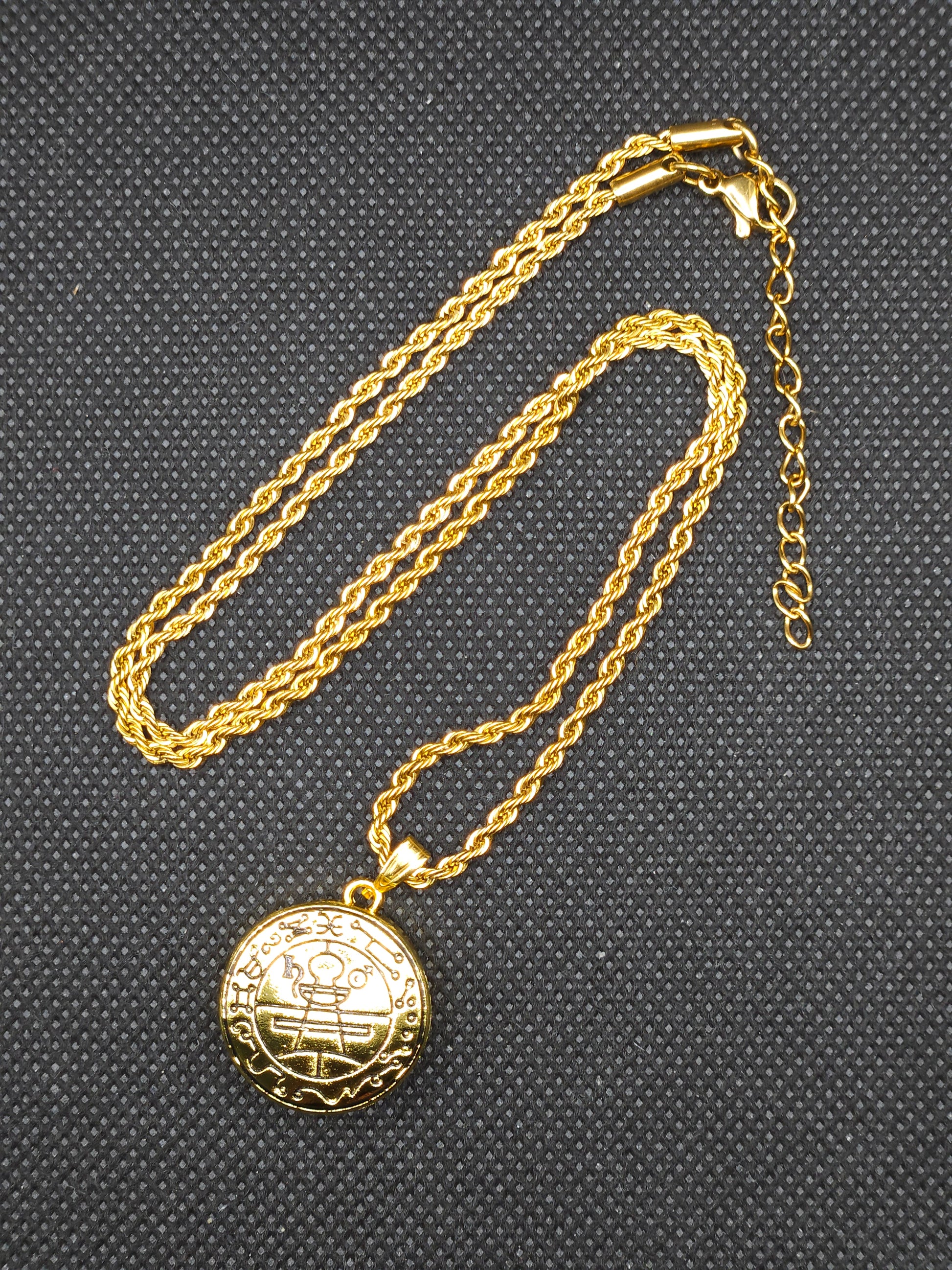 Gold necklace with a round pendant on a textured black background