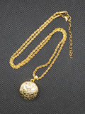 Gold necklace with a round pendant on a textured black background